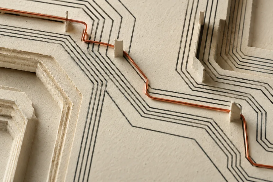 Editorial artwork: fine graphite traces and a copper-orange wire across layered paper.